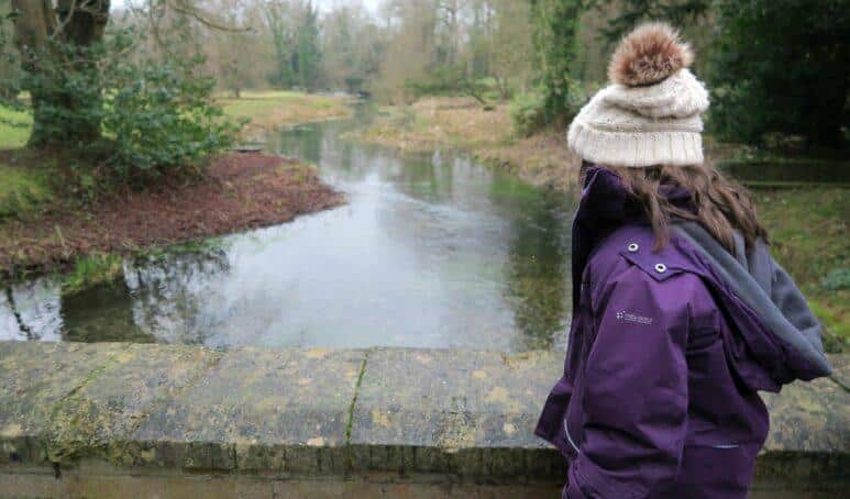 Welford Park Snowdrops and girl stood at river bridge